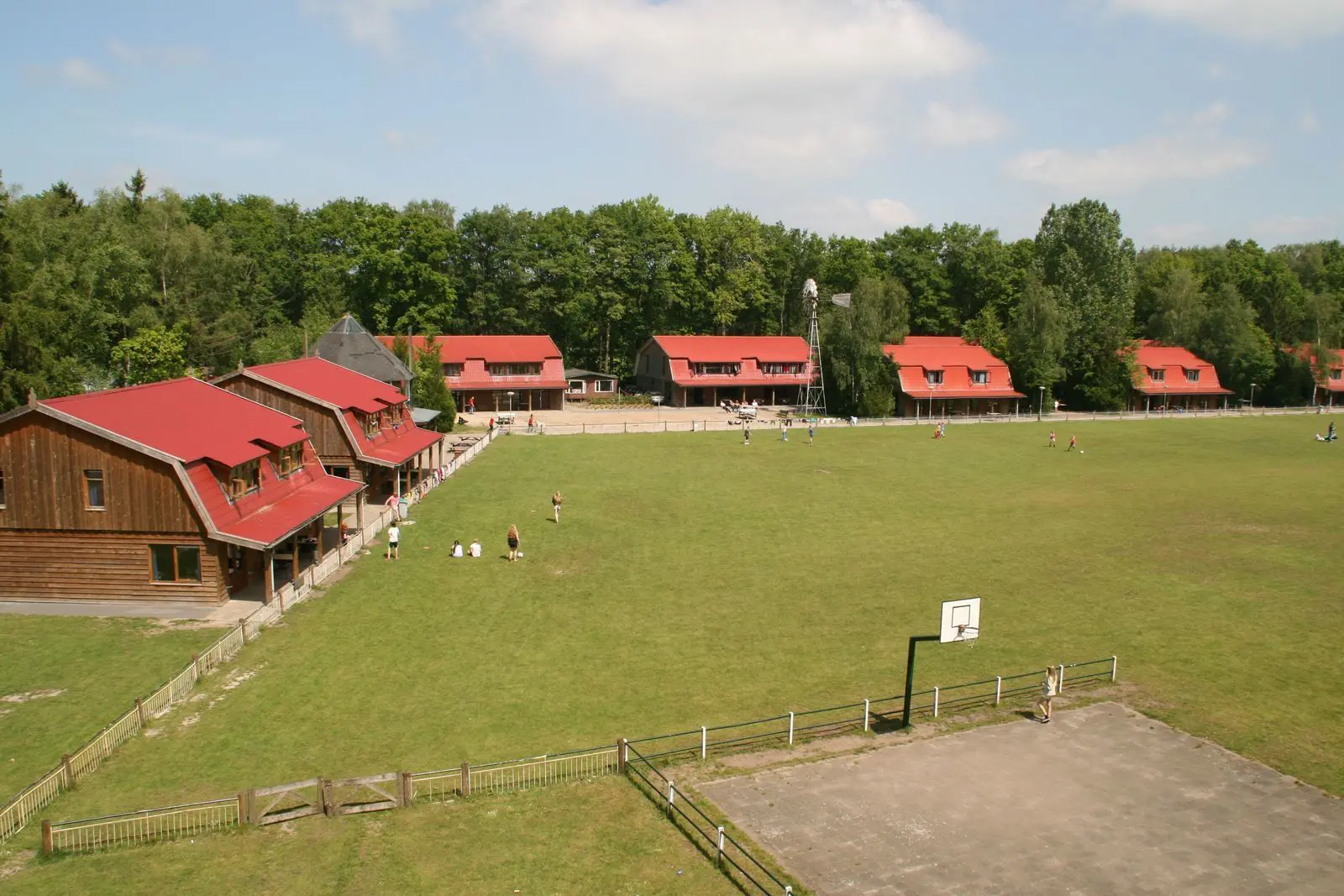 Große Gruppenunterkunft mit mehreren Häusern und Spielwiese in grüner Natur.