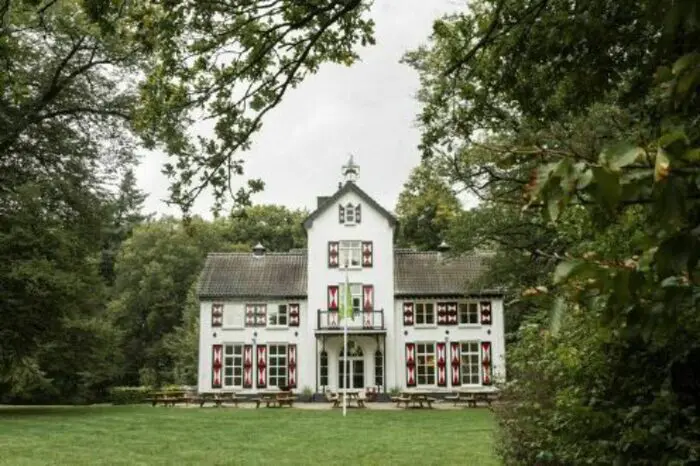 Grote groepsaccommodatie in historisch landhuis midden in het bos met ruime tuin en picknicktafels.